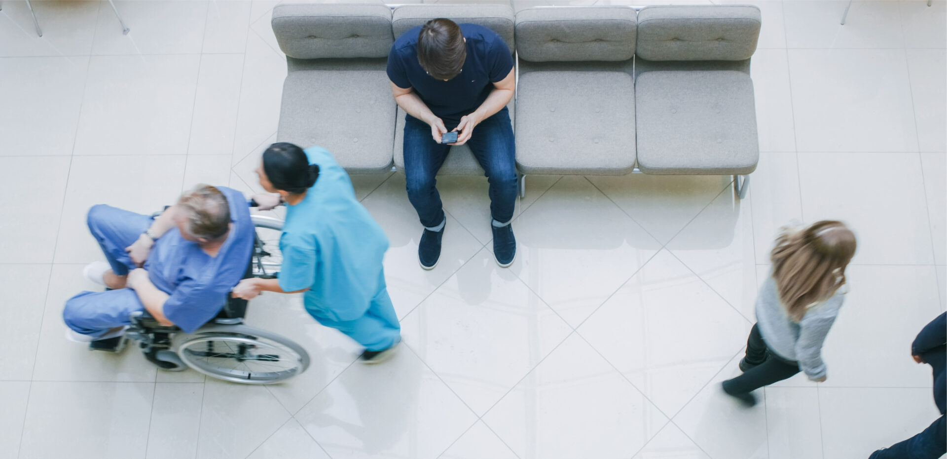 Nurse pushing patient in wheelchair through hospital lobby